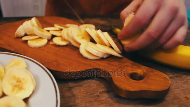 Close-up van snijden banaan op een houten bord met mes — Stockvideo