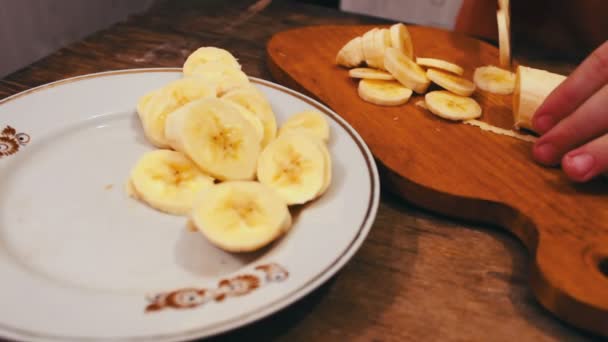 Close-up van snijden banaan op een houten bord met mes — Stockvideo