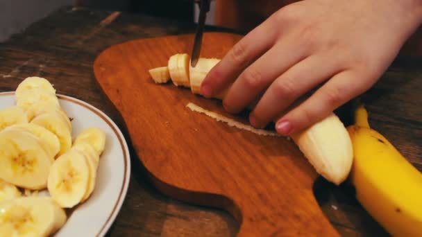 Close-up of cutting banana on wooden board with knife — Stock Video