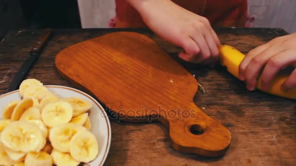 Close-up of cutting banana on wooden board with knife — Stock Video