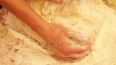 Kadın elleri masada un içinde hamur yoğuruyor.