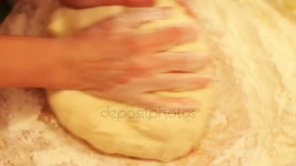 Женские руки месят тесто в муке на столе — стоковое видео