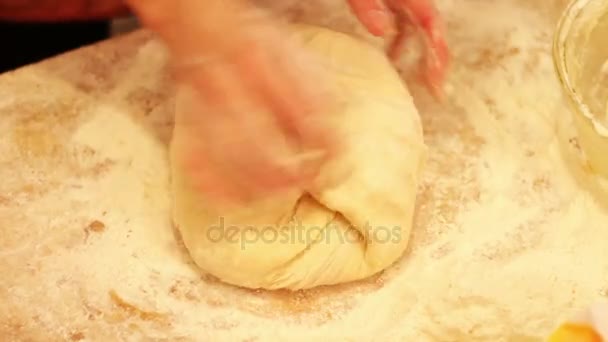 Female hands kneading dough in flour on table