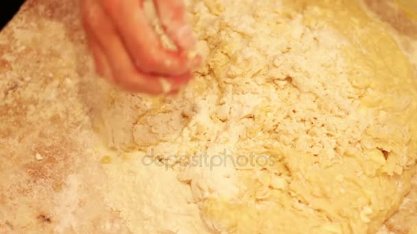 Mains féminines pétrissant la pâte dans la farine sur la table