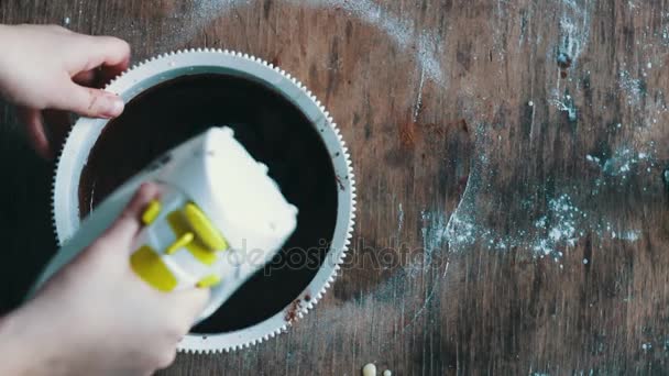 Çikolatalı kurabiye hamuru beyaz bir plastik kapta elektrikli karıştırıcı ile karıştırarak Üstten Görünüm — Stok video