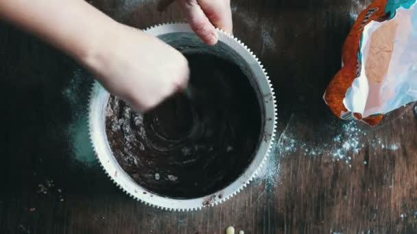Visão superior mexendo massa de biscoito de chocolate com uma colher em uma tigela de plástico branco — Vídeo de Stock
