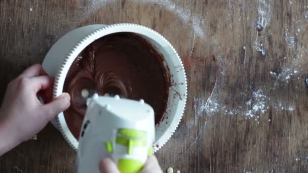 用电动搅拌机在一个白色的塑料碗中搅拌巧克力曲奇饼面团的顶视图 — 图库视频影像