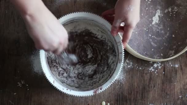 Vue du dessus en remuant la pâte à biscuits au chocolat avec une cuillère dans un bol en plastique blanc — Video