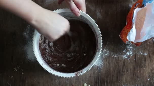 Top view stirring chocolate cookie dough with a spoon in a white plastic bowl — Stock Video