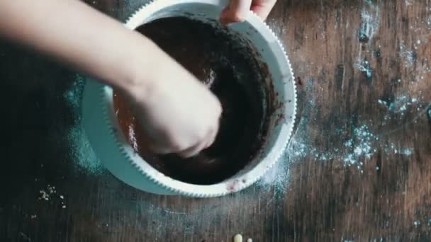 Bovenaanzicht chocolade koekjesdeeg roeren met een lepeltje in een witte plastic kom — Stockvideo