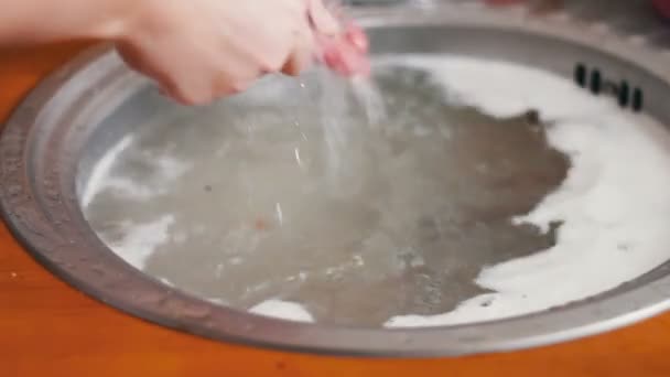 Женщина пытается вымыть посуду до верха засорившейся кухонной раковины — стоковое видео