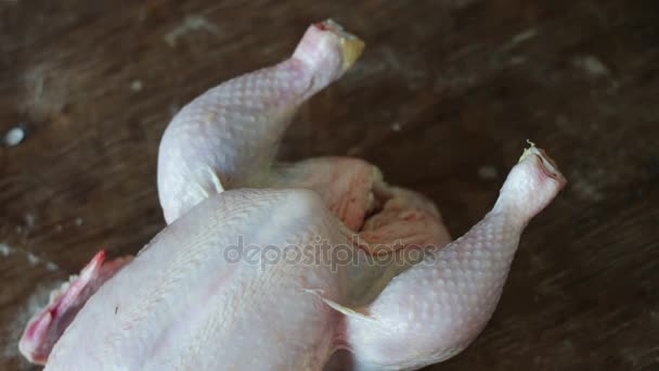 Mains préparant du poulet cru entier sur une plaque de cuisson en bois — Video
