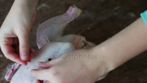 Mains préparant du poulet cru entier sur une plaque de cuisson en bois — Video