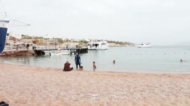 EGITO, SINAI DO SUL, SHARM EL SHEIKH, NOVEMBRO 29, 2016: A família muçulmana banha-se no mar. Uma mulher em hijab com seus filhos nadar no Mar Vermelho . — Vídeo de Stock