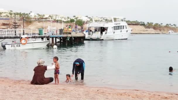 Egypte, South Sinai, Sharm El Sheikh, 29 November 2016: Moslim familie baadt in zee. Een vrouw in een hijab met haar kinderen zwemmen in de rode zee. — Stockvideo