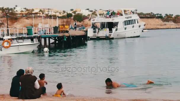 ЕГИПТ, ЮЖНАЯ СИНА, ШАРМ ЭЛЬ-СИХ, 29 ноября 2016 года: Мусульманская семья купается в море. Женщина в хиджабе с детьми плавает в Красном море . — стоковое видео