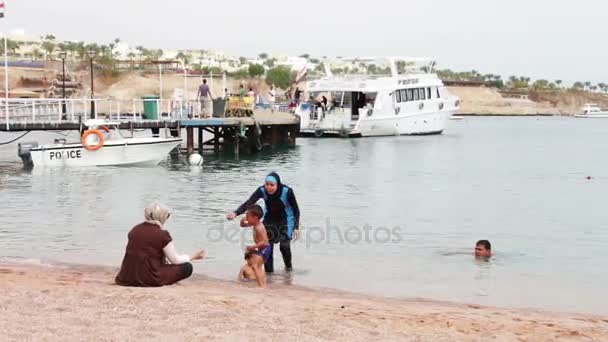 Egypte, South Sinai, Sharm El Sheikh, 29 November 2016: Moslim familie baadt in zee. Een vrouw in een hijab met haar kinderen zwemmen in de rode zee. — Stockvideo