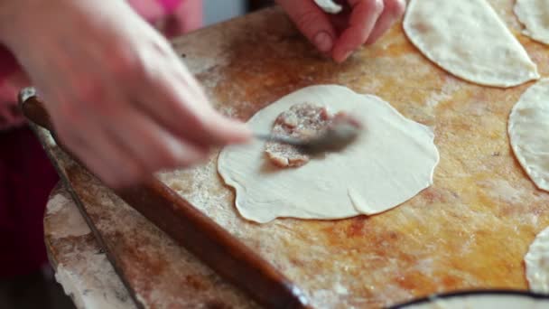 Жінка готує м'ясні пироги, працюючи з тістом і начинкою, крупним планом — стокове відео