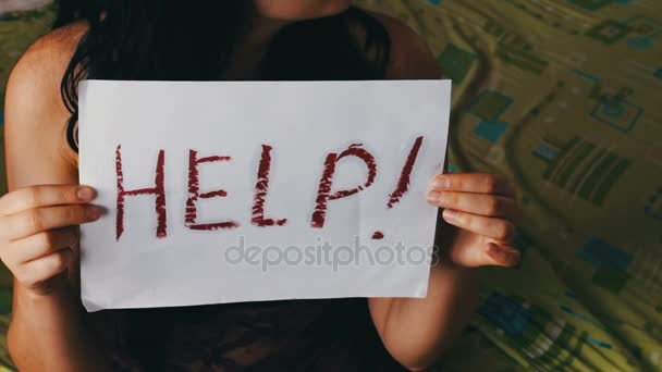 Frightened crying woman holding paper with the word HELP — Stock Video