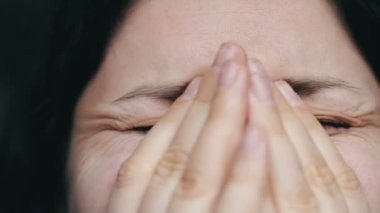 Gözyaşları ile kadın portresi yakından yüzünü elleriyle kapatır