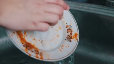 Mutfak lavabosunda bulaşık yıkayan kadın.