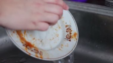 Mutfak lavabosunda bulaşık yıkayan kadın.