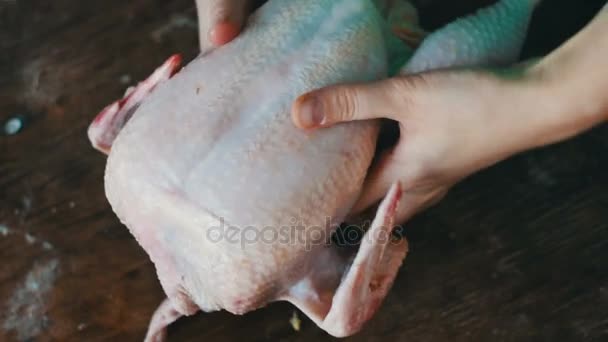 Mãos preparando frango cru inteiro em uma placa de cozinha de madeira — Vídeo de Stock