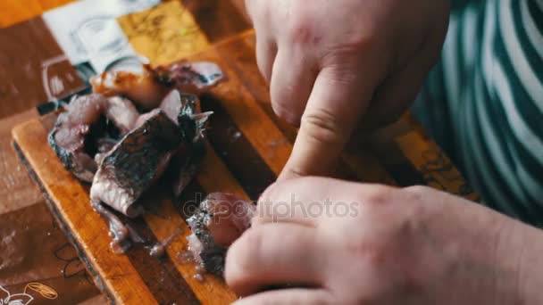 Homem limpa e corta peixe fresco na cozinha da casa . — Vídeo de Stock
