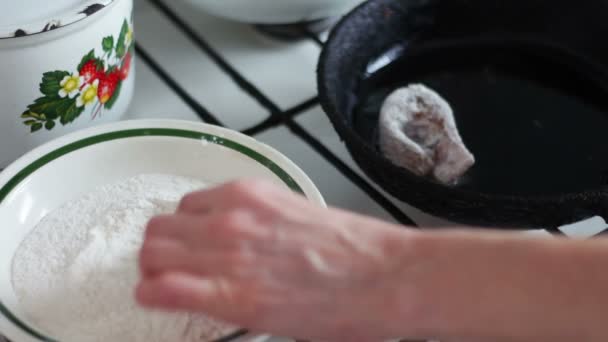 Uma mulher envolve um pedaço de peixe fresco na farinha e coloca-o em uma frigideira — Vídeo de Stock