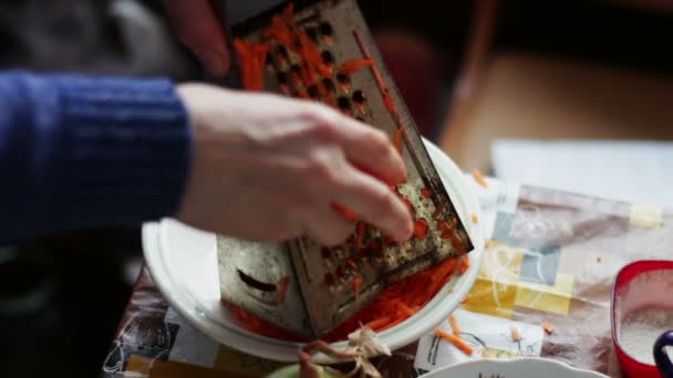 Las hembras frotan las zanahorias al rallador sobre la tabla de cortar — Vídeo de stock