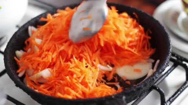 Лук и морковь перемешиваются в старой сковородке — стоковое видео
