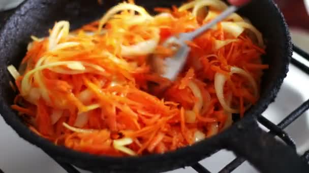 Las zanahorias en rodajas se fríen en una sartén con cebolla, las verduras se guisan — Vídeos de Stock