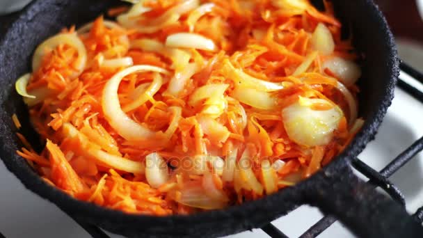 Нарезанные морковь жарят в сковороде с луком, овощи тушат — стоковое видео