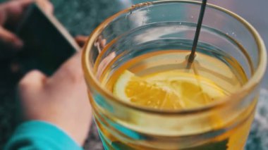 Limonlu çay tarçın ile yanındaki bir kafede bir smartphone oynamak bir çocuk