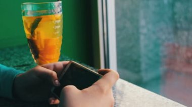 Limonlu çay tarçın ile yanındaki bir kafede bir smartphone oynamak bir çocuk