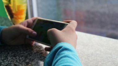Genç genç Cafe tarçın ile limon çayı yanındaki smartphone cep telefonu ile oyun oynama