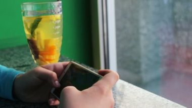 Genç genç Cafe tarçın ile limon çayı yanındaki smartphone cep telefonu ile oyun oynama