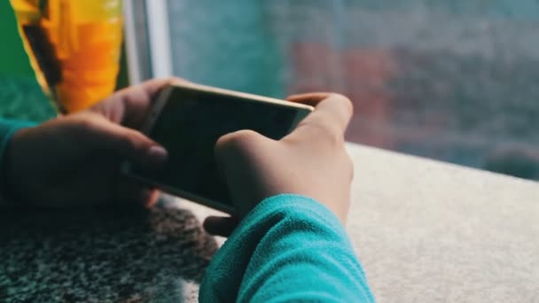 Un garçon joue sur un smartphone dans un café à côté du thé au citron à la cannelle — Video