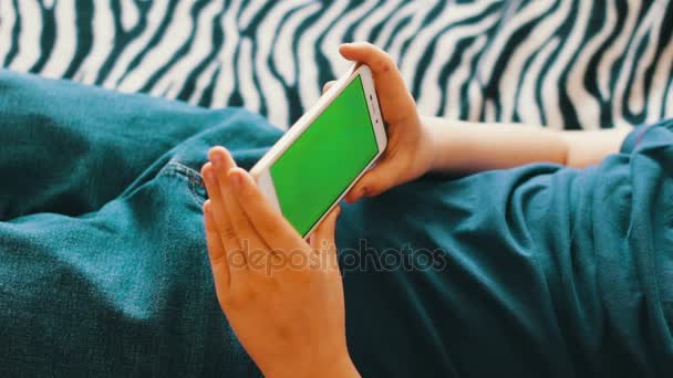 Teenager with Smartphone chroma key surfing on Internet on couch at home — Stock Video