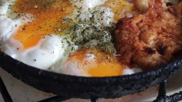 Stekta ägg i en stekpanna på nära håll och stekt kyckling nuggets med kryddor — Stockvideo