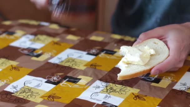 Homem está espalhando manteiga em um pão ao lado de uma xícara de café quente — Vídeo de Stock