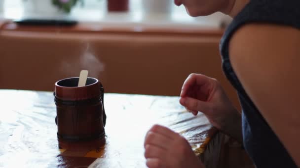 Een meisje drinkt een ochtend die is stomen — Stockvideo