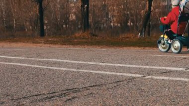 Işık kot pantolon ve ceket genç bir anne bir çocukla mavi bicycle.walking ayakları kaldırım üzerinde yürür.