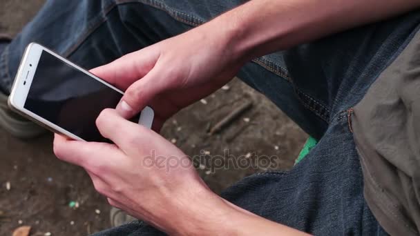 Молодой человек играет на мобильном телефоне, смотрит на экран — стоковое видео