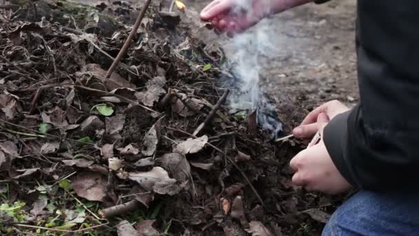 Подростки разводят костёр из сухих старых листьев, загрязняют окружающую среду — стоковое видео
