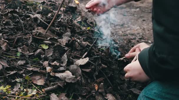 Подростки разводят костёр из сухих старых листьев, загрязняют окружающую среду — стоковое видео