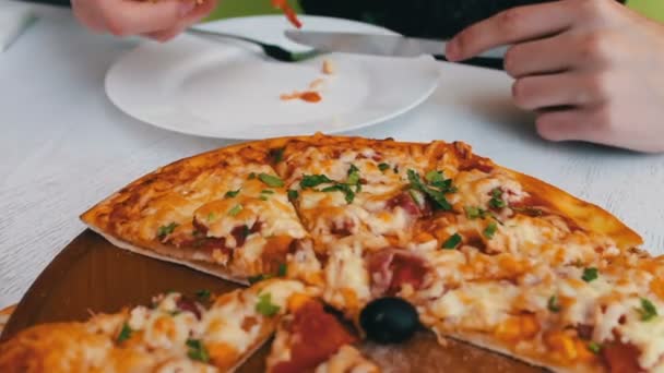 Uomo che mangia una deliziosa pizza appena sfornata con formaggio, mais, pomodori, carne ed erbe in un elegante sfondo bianco, cucina italiana — Video Stock