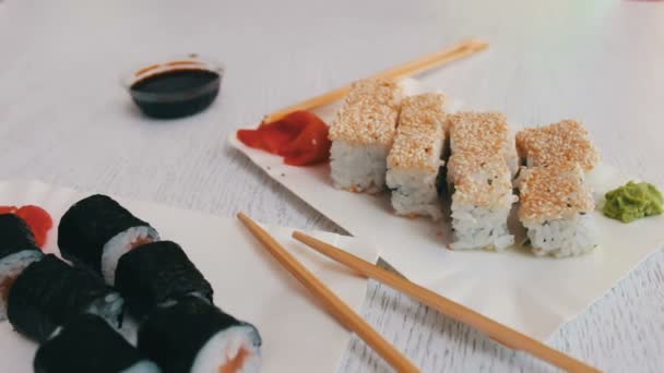 Cocina japonesa de sushi-maki con salmón, jengibre rosa, wasabi verde y salsa de soja en platos blancos — Vídeos de Stock