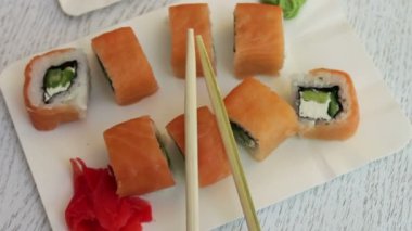 Somon zencefil ve peynir wasabi ve bir kafede beyaz plakalar üzerinde ahşap sopa ile taze lezzetli suşi