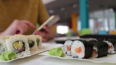 Suşi, Japon mutfağı Smartphone'da yazarak ve masada kafede muhatap ile iletişim kız oturur vardır